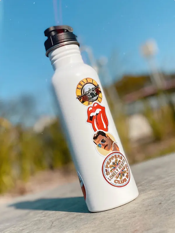 Botella blanca con stickers de bandas de rock