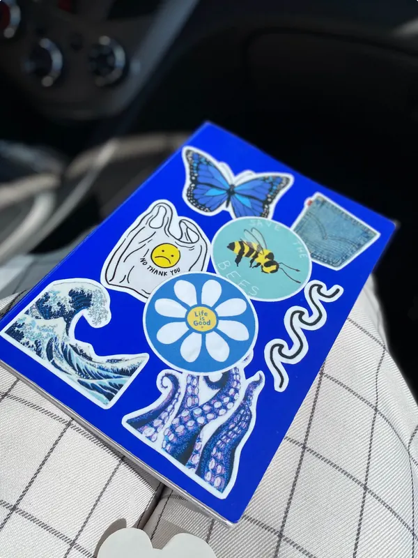 Cuaderno azul con stickers de mariposa, ola y abeja