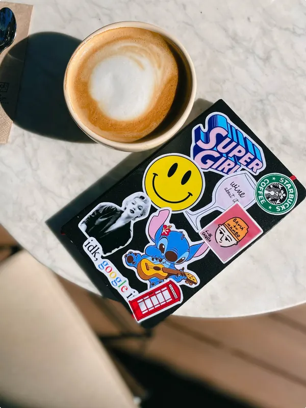 Libreta negra con stickers junto a un café