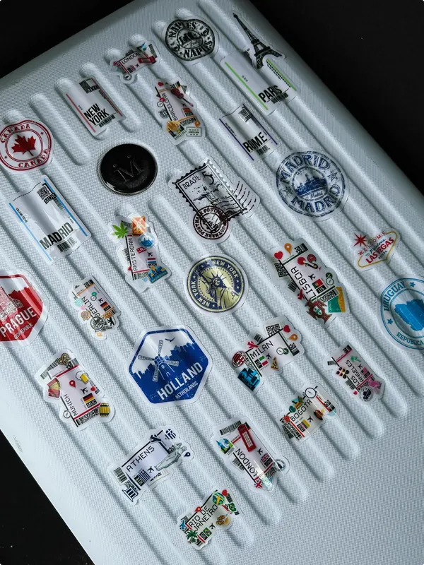Valija blanca con stickers de ciudades del mundo